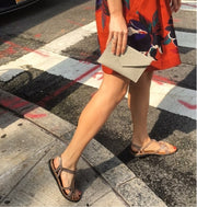 Image shows a stylised image of a model influencer wearig a red dress with a modern flora print.The Model/Influencer is about to cross the road at a zebra crossing. The model/influencer is wearing Naot Dorith in Radiant Copper