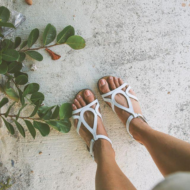 Picture shows an influencer model wearing the white sandal, Dorith. The shot is of the feet in the sandal. 